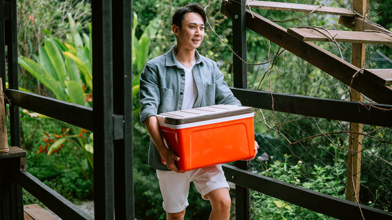 man carrying orange cooler
