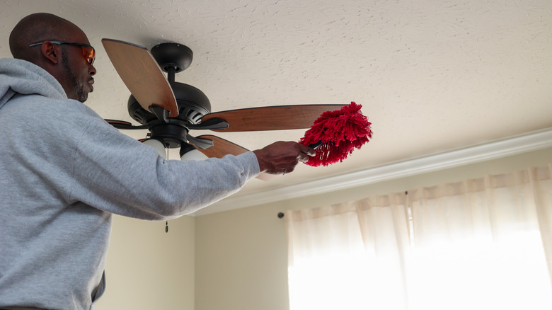 Man dusting a ceiling fan