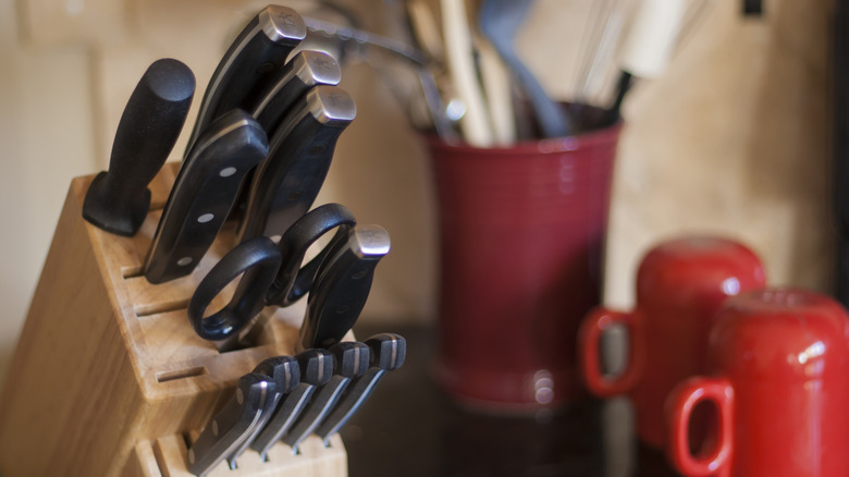 Kitchen knives and other utensils in a knife block on a kitchen counter