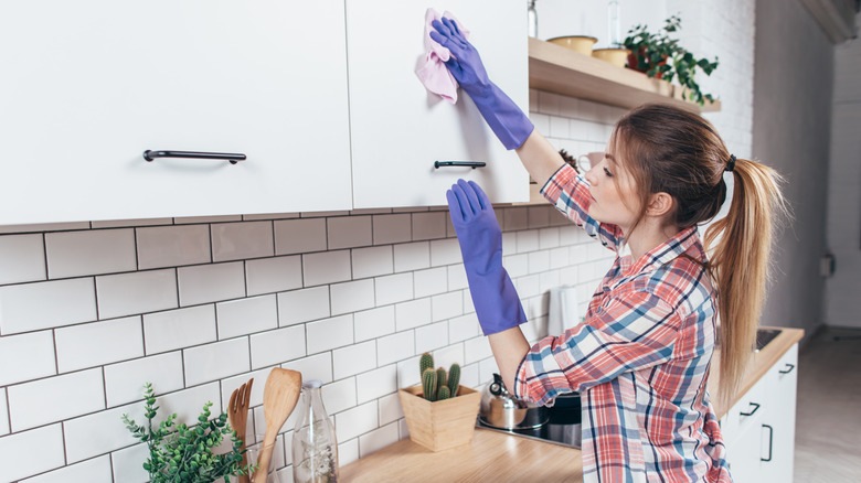 Woman cleans kitchen cabinets