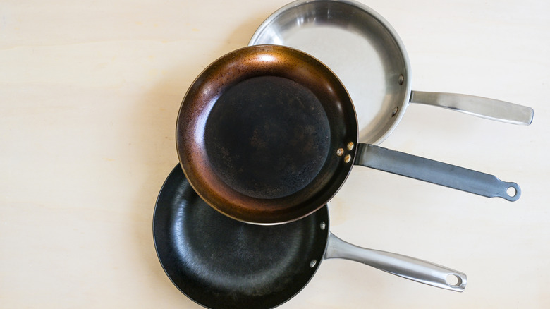 Three nonstick pans that are black and silver on counter.