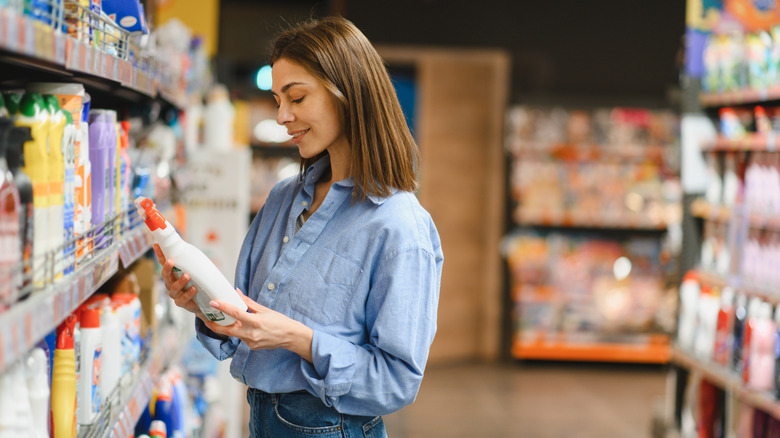 Woman holding a cleaning product in her hands while shopping at a store