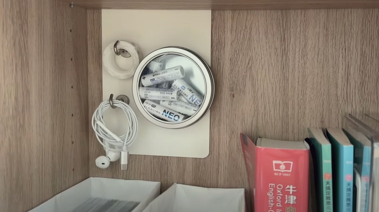 Small items stored on the back of a bookshelf using magnets