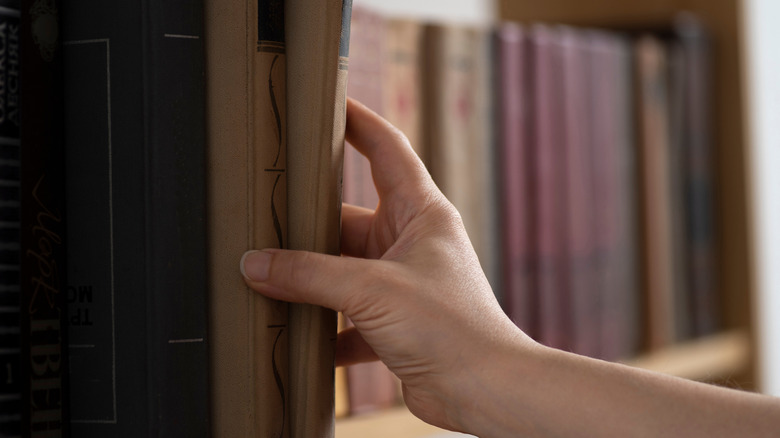 A person pulling books from a shelf