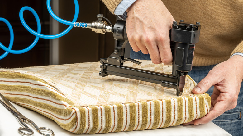 A hand using a pneumatic staple gun