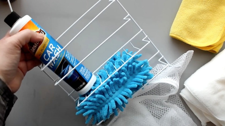 Hand putting car cleaner in wire shower caddy with