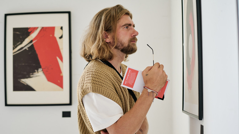 Man looking closely at a piece of framed art in a gallery