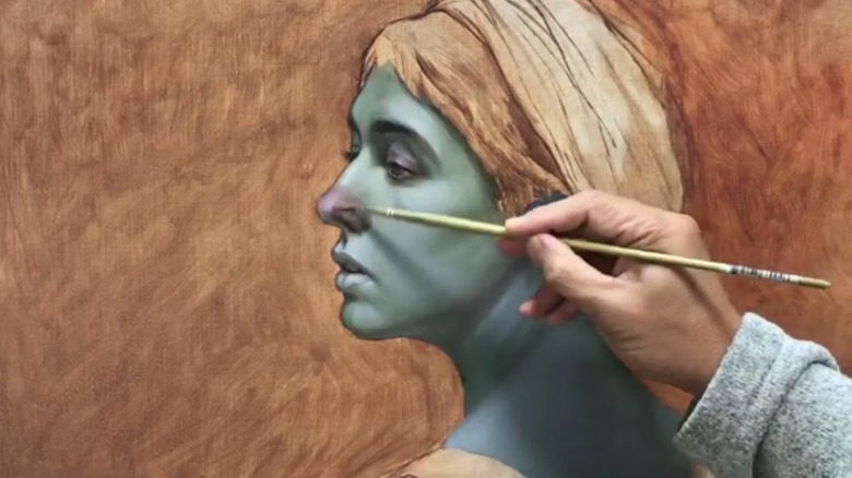 Artist's hand glazing a painting with oil paint