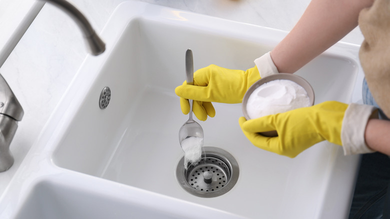 adding spoonful of baking soda to sink