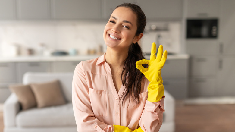 A smiling woman wearing yellow rubber gloves