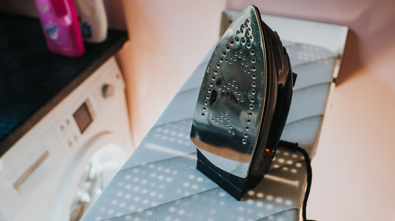 an ironing board rests in a small and cramped laundry room