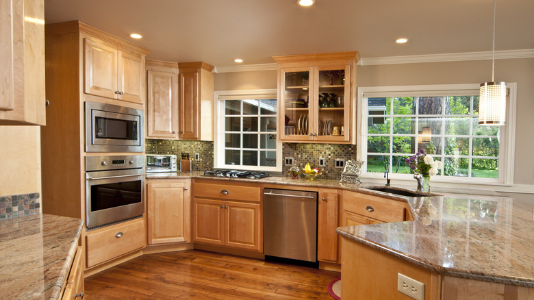 dated oak cabinets with orange hue and warm kitchen lighting