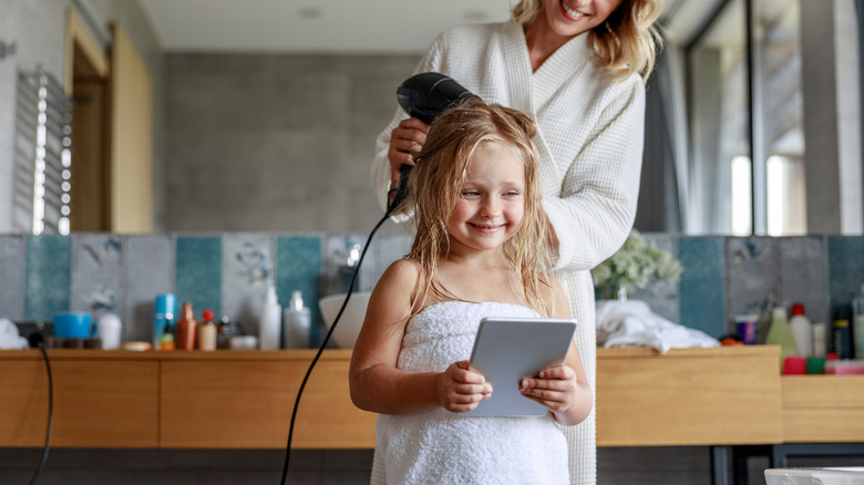 mother and daughter using hairdryer