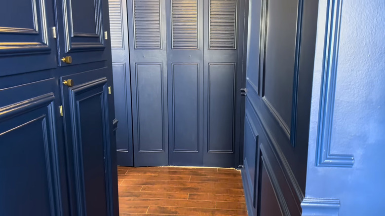 A hallway with wood flooring and dark blue trim and walls