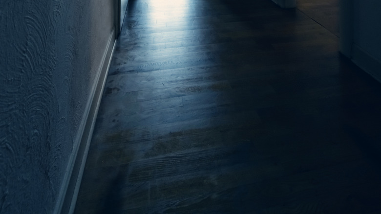 A dark hallway with bright light coming from an open door at the very end