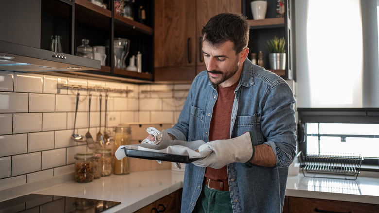 A person cleaning a baking tray with paper towels