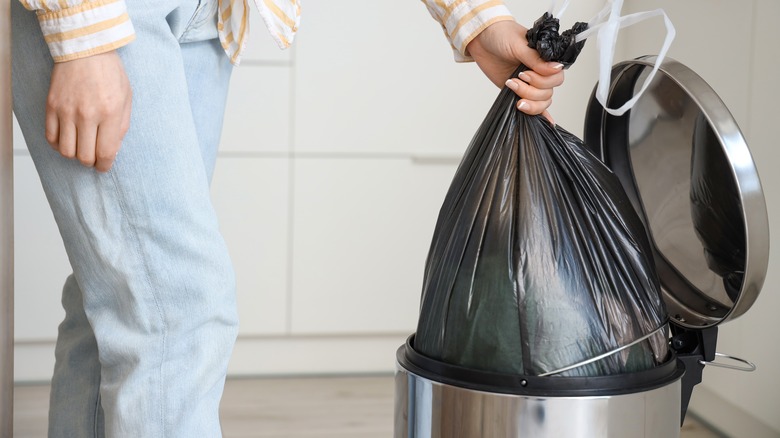 Person taking bag out of kitchen trash can