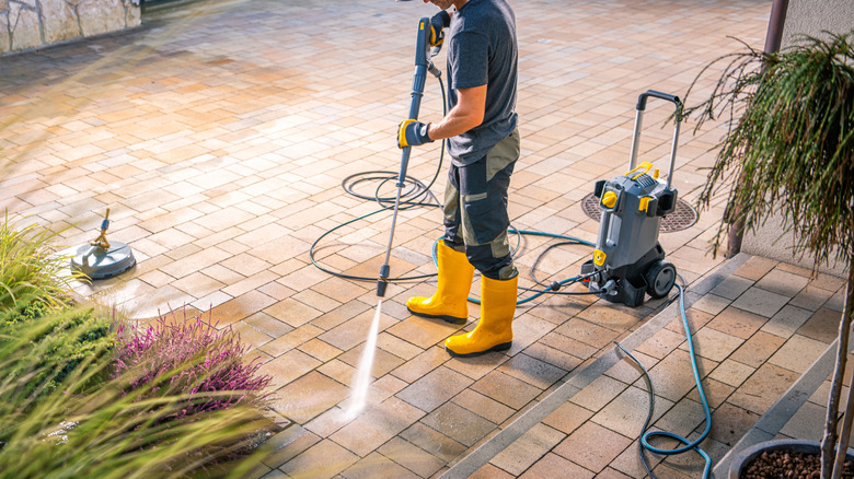 A person washing a patio with a pressure washer