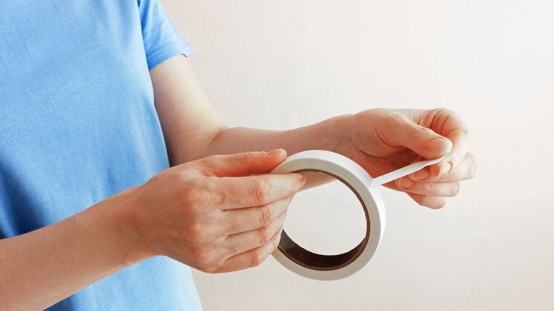 person holding roll of masking tape