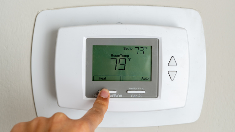Finger adjusting the temperature on a thermostat.