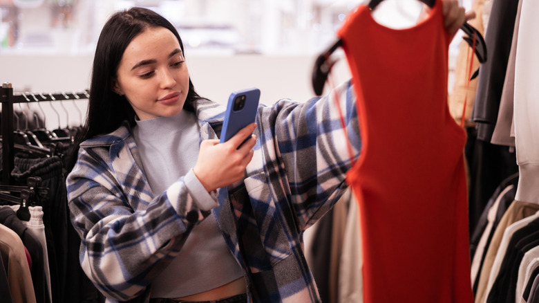 A woman taking a picture of a red dress in a store