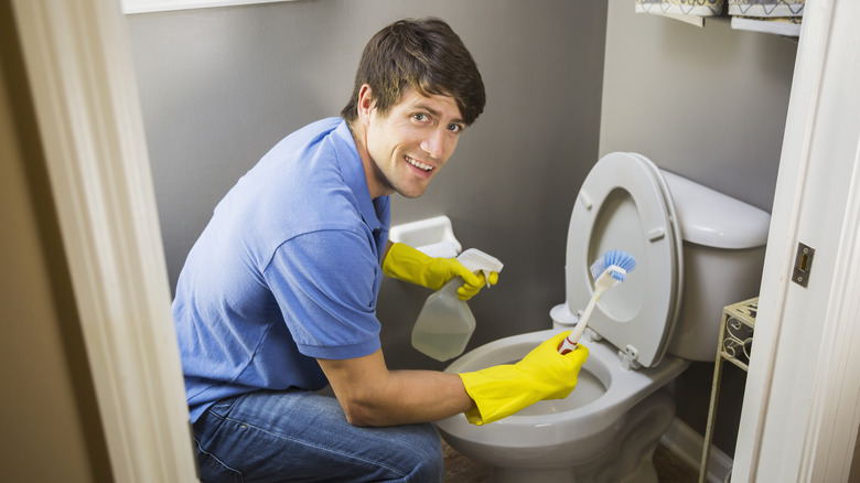 smiling man cleaning toilet