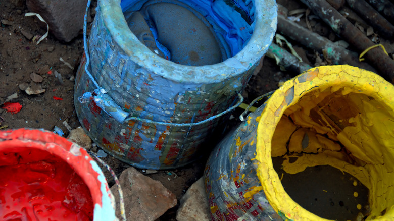 Open paint cans containing dried blue, red, and yellow paint