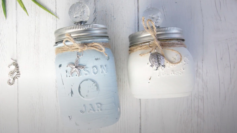 Nautical-themed glass jars painted white and baby blue on a white wooden surface