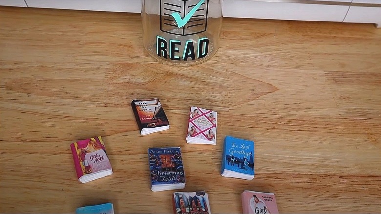 Mini DIY book charms on a desk next to a glass jar