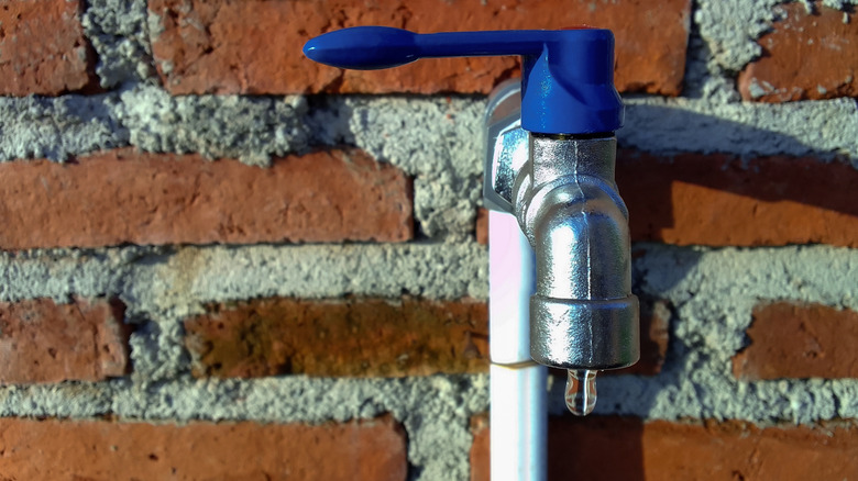 A prominent water tap mounted on a brick house exterior