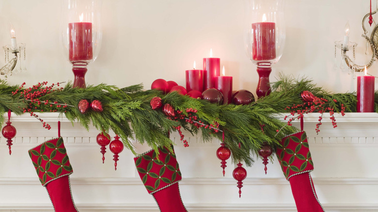 Christmas garland and red stockings on white fireplace mantle