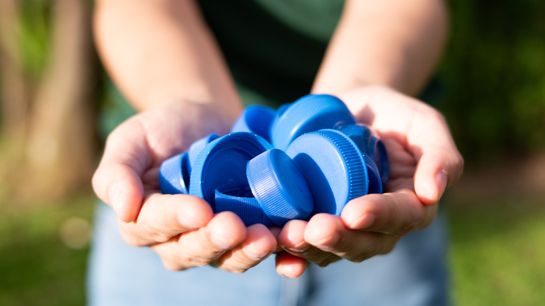 A person holding blue bottle caps