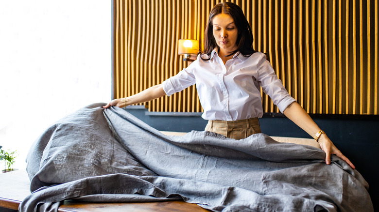 woman laying a tablecloth onto a table