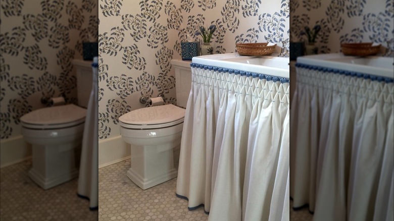 sewn white sink skirt in bathroom with patterned wallpaper