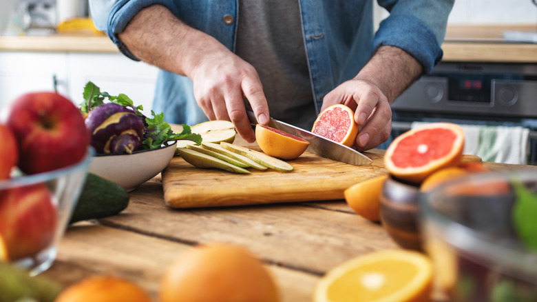 Man in a kitchen cutting up produce