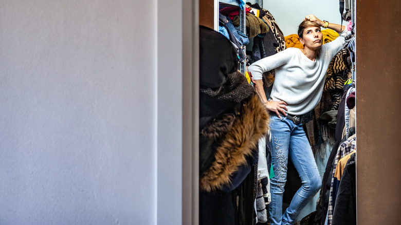 Woman standing in messy closet