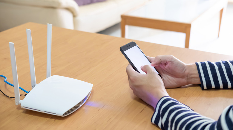 Someone using their smartphone to log into a wireless router.