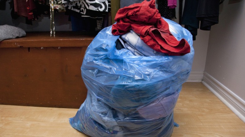 Plastic bag full of old clothes in closet