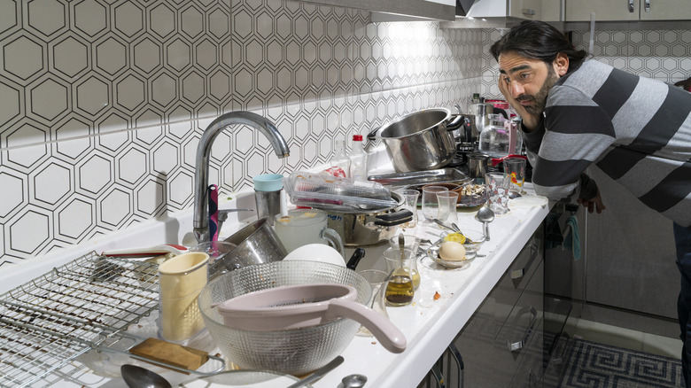 Man staring at kitchen clutter