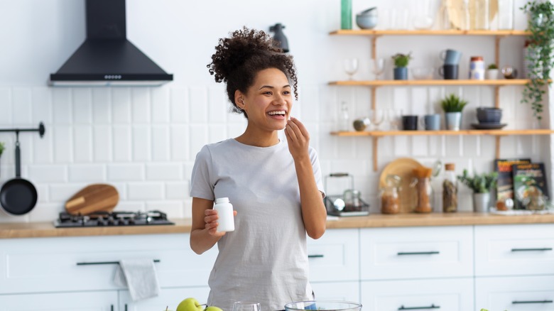 Woman taking vitamins in the kitchen
