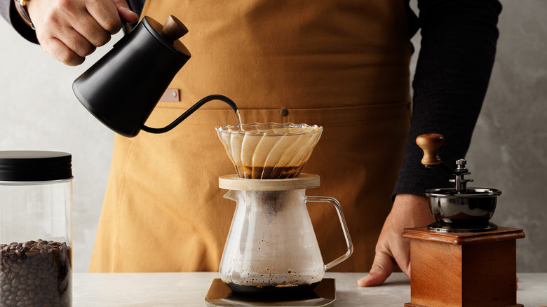 Man pours water over coffee grounds