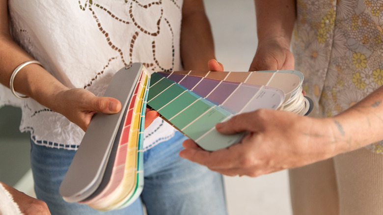 Close-up of two women holding and browsing paint swatches