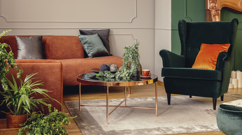 Living room with green accent wall, green accent chair, brown couch, and wood floors.
