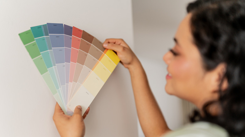A person holding a variety of color swatches up against the wall