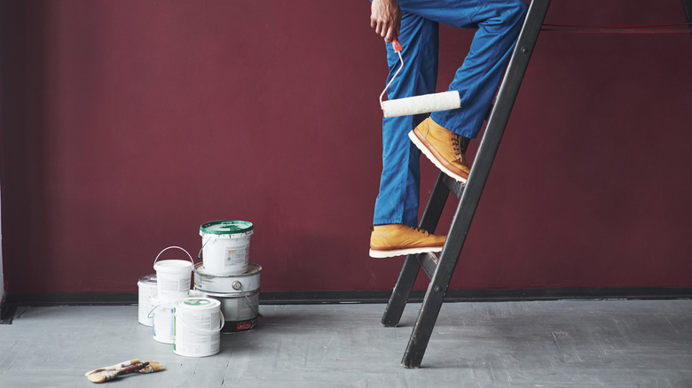 A person walking up a ladder holding a paint roller