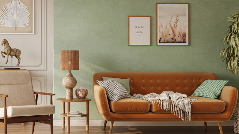 A living room with green walls and an orange sofa