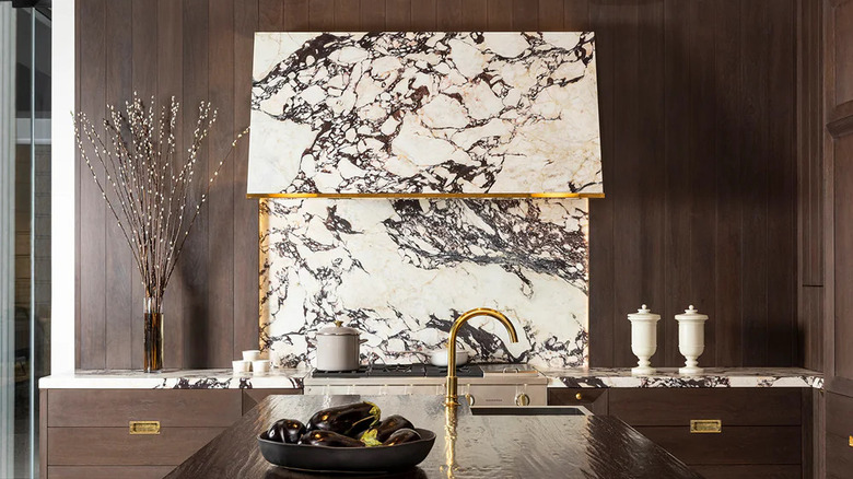 A beautifully designed kitchen decorated in a white, gold, brown, and marble color palette.
