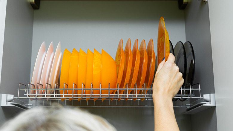 White, orange, and black dishware on rack inside cabinet
