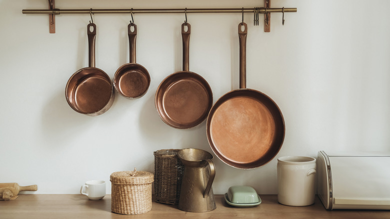 Brass pots hang on the wall of the kitchen with accent pieces on the counter