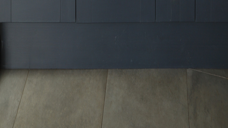 Dark navy blue cabinets under a sink with a brass faucet